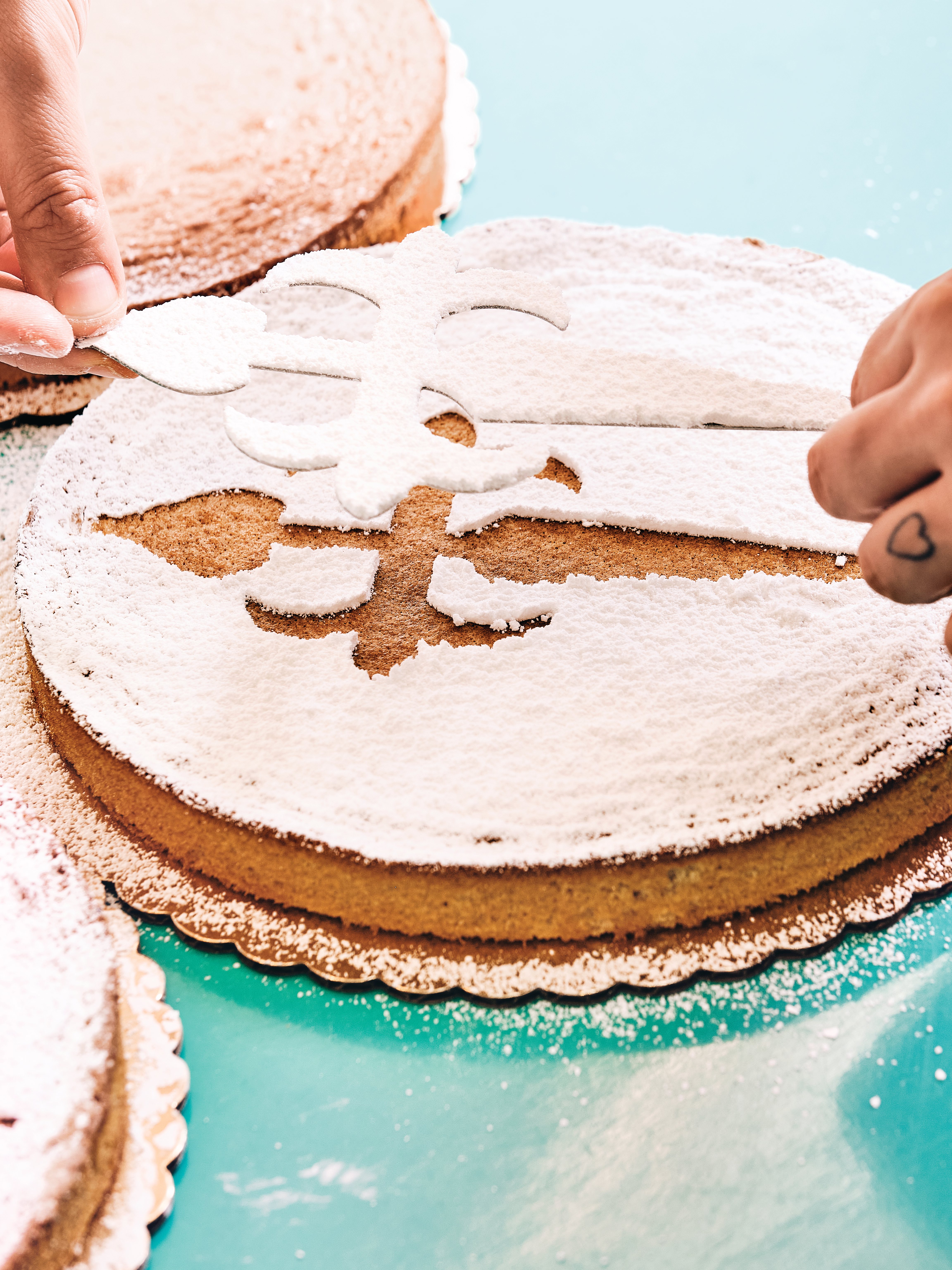 Tarta de Santiago being dusted with icing sugar using the traditional cross stencil.